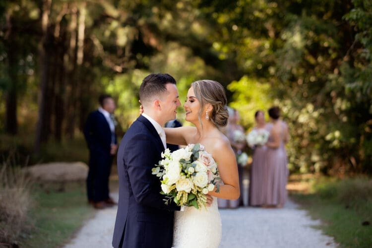 Wedding couple with bridal party in the background outdoors