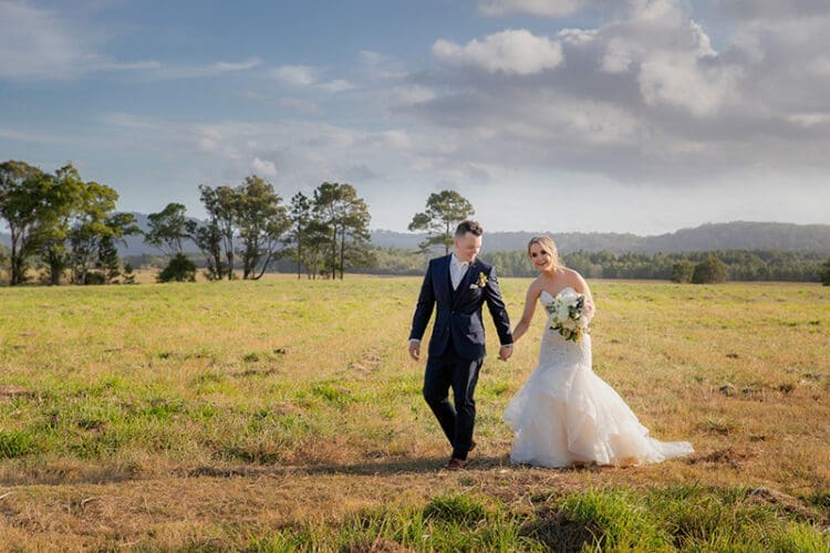 Bride and Groom walk in a field on the Tweed Coast