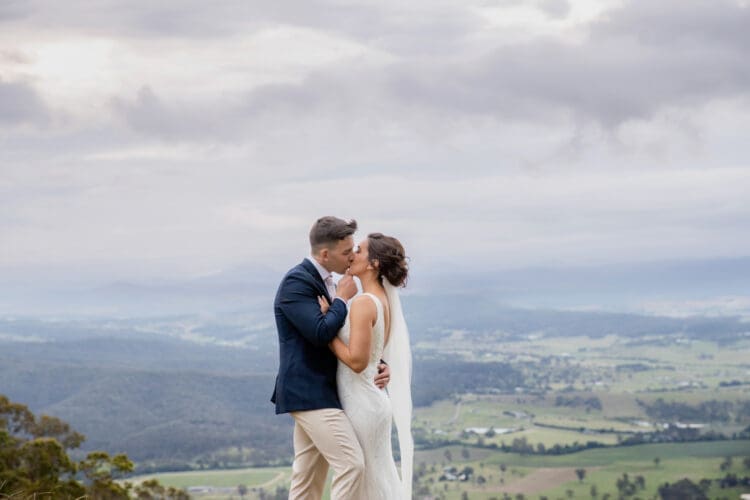 A bride and groom kiss at the lookout in Tamborine Mountain