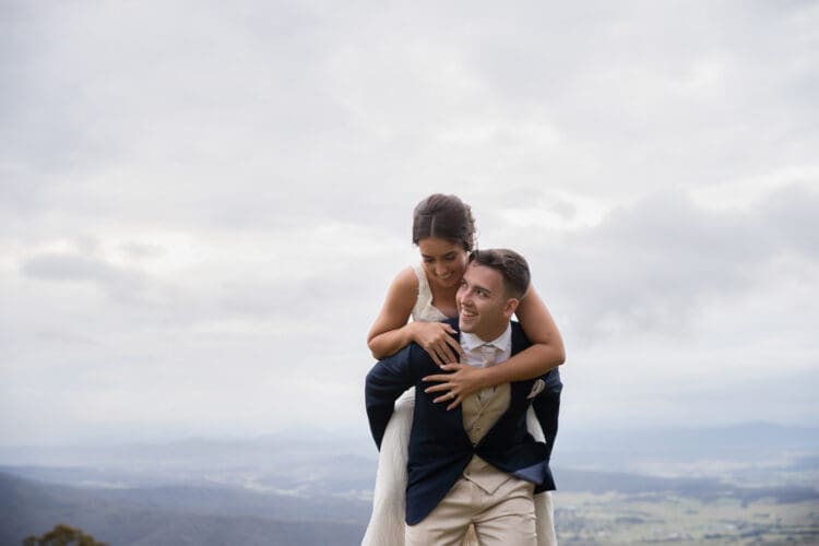 A bride and groom have fun for their wedding photography at the lookout in Tamborine Mountain