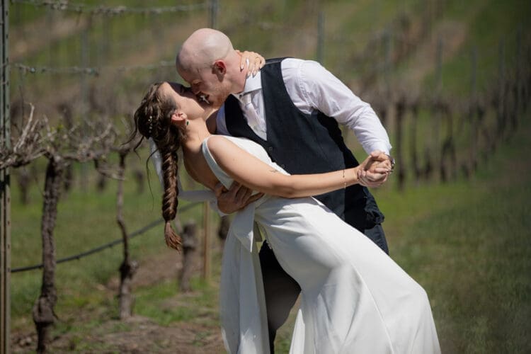 Groom dipping and kissing his bride with the vineyards in the background