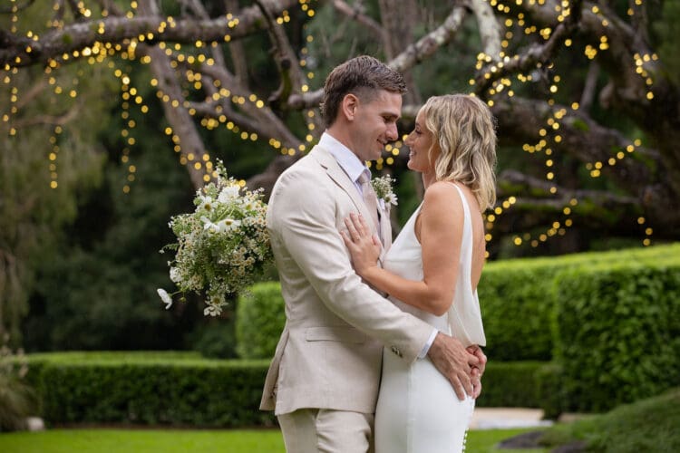 Bride and groom share a romantic moment under fairy lights at Braeside Gin House Creek Estate